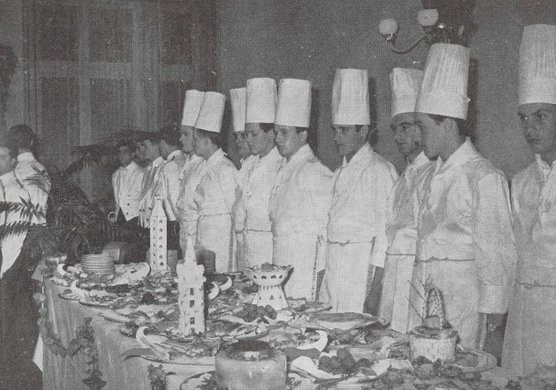 I partecipanti al concorso di cucina in perfetto allineamento dietro la tavola imbandita