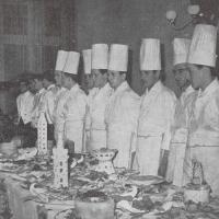 I partecipanti al concorso di cucina in perfetto allineamento dietro la tavola imbandita